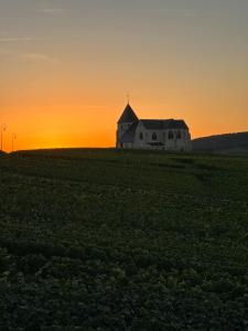 a church in the middle of a field at sunset at AU COEUR DU TERROIR CHAMPENOIS in Chavot-Courcourt