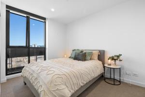 Dormitorio blanco con cama y ventana grande en Skyline Luxury Retreat: Gym, Pool & Cinema, en Adelaida