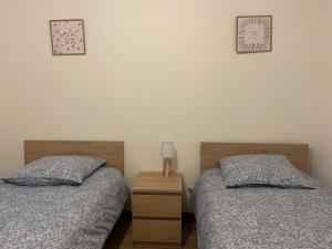 1 dormitorio con 2 camas y mesita de noche con 2 camas en maison entièrement rénovée centre de Luché pringé, en Luché-Pringé