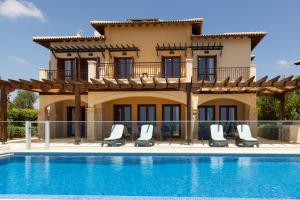a villa with a swimming pool in front of a house at Aphrodite Hills Rentals - Mythos in Kouklia