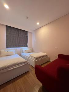 a bedroom with two beds and a red couch at 3415B Mipec Riverside nice view in Hanoi