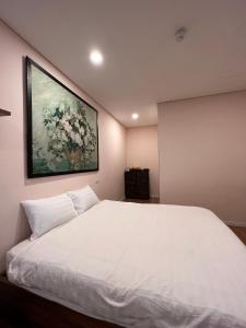 a bedroom with a white bed with a painting on the wall at 3415B Mipec Riverside nice view in Hanoi