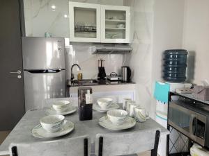 a kitchen with a table with four cups and plates on it at Palam Mansion at Apartment One Residence in Batam Center