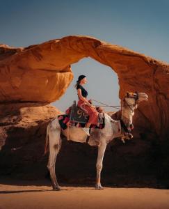 a woman is riding a camel in the desert at Jad desert camp in Wadi Rum