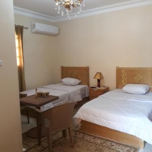 a bedroom with two beds and a table and a chandelier at Nana Pyramids Guest House in Cairo