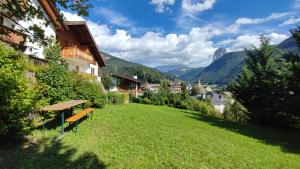 una panchina su una collina erbosa con montagne sullo sfondo di Villa Suredl a Ortisei