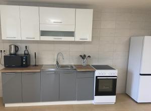 eine Küche mit weißen Schränken, Spüle und Kühlschrank in der Unterkunft Eglutė in Šilutė