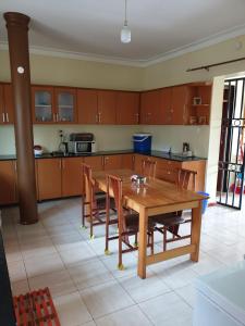uma cozinha com uma mesa de madeira e cadeiras em 3-Bedroom Mbarara Apartment with Optional Farm Tour em Mbarara