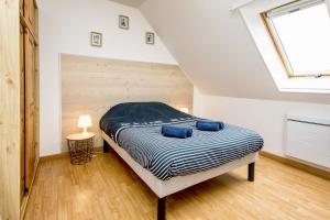 a bedroom with a bed with blue pillows on it at L’Albizia … Maison familiale proche des plages in Plougoulm