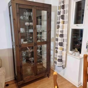 a wooden cabinet with glass doors in a living room at cosy one bed Mill hill in Hendon