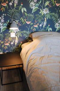 een slaapkamer met een bed en een muur met bloemenbehang bij Vrijstaande woning Drenthe bij het bos. 