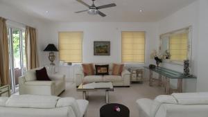a living room with white furniture and a ceiling fan at Las Brisas Villa - Chateau Elysium in Beau Vallon