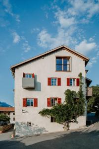 a white building with red windows and a tree at Zum Riesen Historic Refugium in Laces