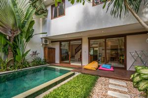 a villa with a swimming pool in front of a house at Du Ciel Villa by Hombali in Canggu