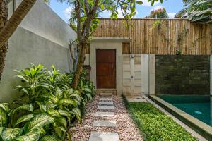 a garden with a pathway leading to a house with a door at Du Ciel Villa by Hombali in Canggu