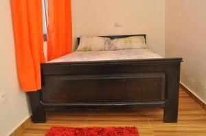 Cama en habitación con cortina naranja en Motel Ayélawadjè Palm Beach, en Ekpé