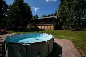 a hot tub in a yard with a building in the background at Dom Wakacyjny - Las i rzeka 