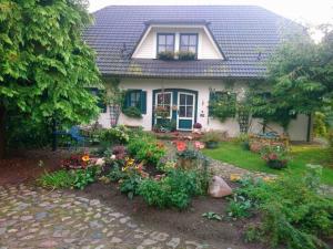 une maison blanche avec des fleurs dans la cour avant dans l'établissement Ferienwohnungen "Christelhof", à Wustrow