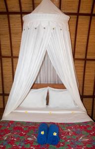 a bed with a canopy with blue shoes on it at Villa Rika in Gili Trawangan
