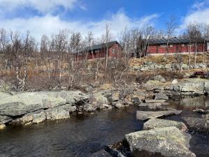 a river with rocks in front of a red building at River view in Hovet
