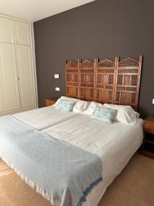 1 dormitorio con 1 cama grande y cabecero de madera en House Oasis Corralejo en Corralejo