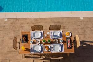 a table with plates of food on it next to a pool at Villa Calleste in Kalamitsi