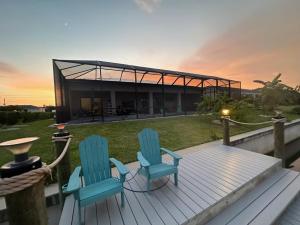 zwei Stühle auf einer Terrasse mit einem Haus im Hintergrund in der Unterkunft Villa Mangifera with Salt Water Pool & Spa, EV-Loading in Cape Coral