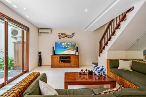 a living room with a couch and a tv at Du Ciel Villa by Hombali in Canggu