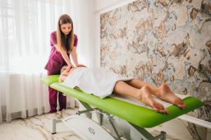 una mujer acostada sobre un paciente en una cama en Aqua Metropol, en Băile Felix