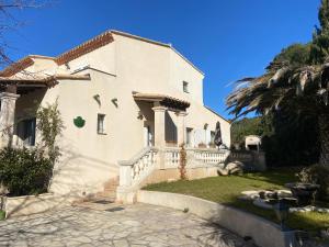 een groot wit huis met een palmboom bij Grande chambre dans villa proche de la plage in Sète