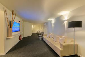 une salle d'attente avec un canapé blanc et une télévision à écran plat dans l'établissement IROCO HOSTAL, à Cala d´Or