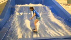 una joven montando una ola en un tobogán de agua en GoldenGlow Apartment 15 MIN Airport, en Dublín