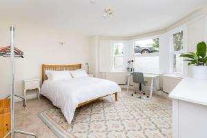 a white bedroom with a bed and a desk at Spacious 2 bed Garden Flat by the Thames+parking in London