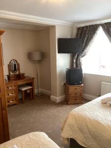 a bedroom with a bed and a tv and a window at Barons Court in Great Yarmouth