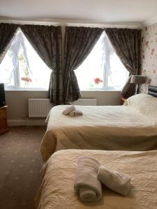 a hotel room with two beds and two windows at Barons Court in Great Yarmouth