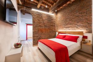 a bedroom with a brick wall and a bed with a red blanket at Affittacamere La Rocca Campiglia in Campiglia Marittima