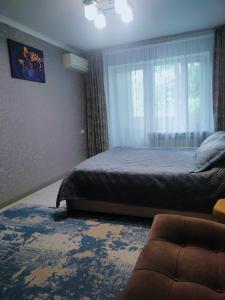 1 dormitorio con cama, ventana y sofá en Квартира на Панфилова "Арбат" 1 комн en Almaty