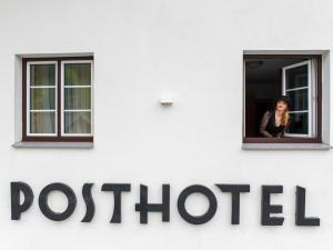une femme regarde par la fenêtre d'un bureau de poste dans l'établissement Posthotel Lechtal, à Holzgau