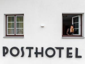 Eine Frau schaut aus dem Fenster einer Post. in der Unterkunft Posthotel Lechtal in Holzgau