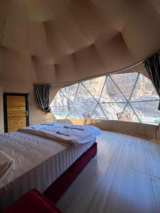 Cette chambre comprend un grand lit et une grande fenêtre. dans l'établissement Hilton Wadi rum, à Disah