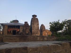 a temple with two large stone towers next to a wall at Himalaya Mount View Resort Kausani in Kausani