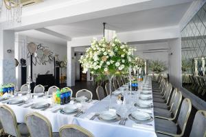 デンビツアにあるHotel Lord Dębicaの白い皿と花が飾られた長テーブル