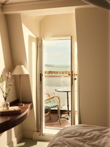 a bedroom with a door open to a balcony with a table at No 42 by GuestHouse, Margate in Margate