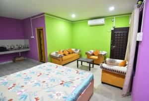 ein Schlafzimmer mit grünen und violetten Wänden sowie einem Bett und Sofas in der Unterkunft Hira Panidihing Homestay in Sibsāgar