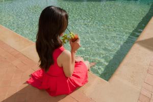 una donna seduta accanto a una piscina che mangia una mela di Villa Athena Resort a Agrigento