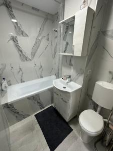 a white bathroom with a sink and a toilet at Cozy Apartment in Rădăuţi