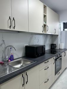 a kitchen with a sink and a microwave at Cozy Apartment in Rădăuţi