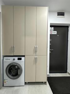 a laundry room with a washing machine and cabinets at Cozy Apartment in Rădăuţi