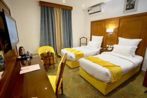 um quarto de hotel com duas camas e uma secretária em Rose Jeddah Hotel em Jidá