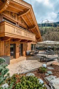 a large wooden house with a patio with benches at Apartmenthaus Wiesenhof in Aschau